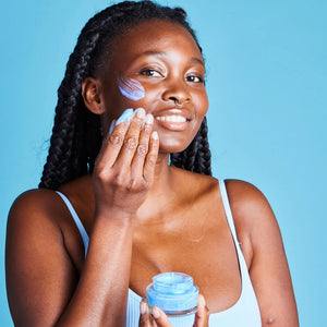 Woman applying Blue butterfly sleep mask to her face against a blue background