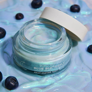 Jar of 'Blue Butterfly' fruit enzyme sleep mask with blueberries on a textured background