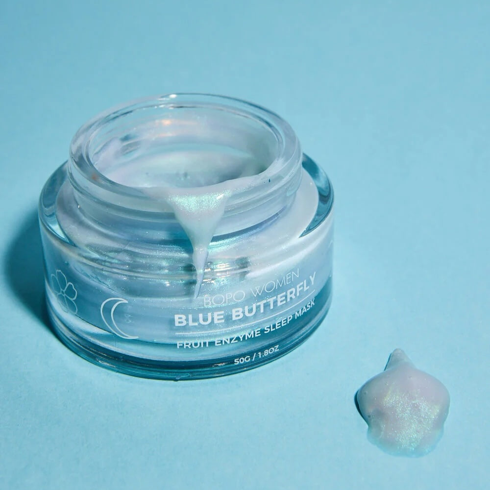 Jar of 'Blue Butterfly' fruit enzyme sleep mask on a light blue background