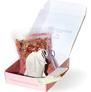 Steep 'n' soak blushing bath tea with dried botanicals, a white tea bag, and a booklet in a pink box on a white background.