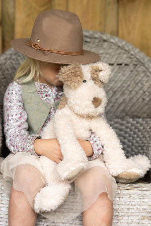 Girl holding Buddy the Dog soft toy. Buddy is wearing a neck bandana embroidered with his name.