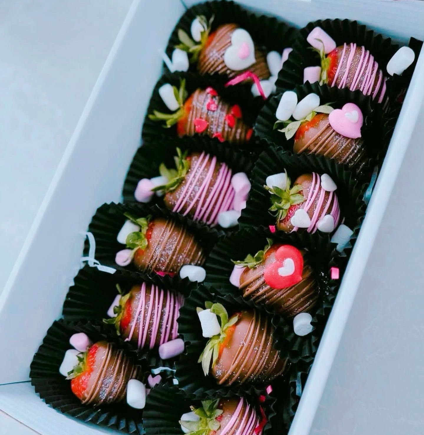 Chocolate-covered strawberries with decorative elements in a white container
