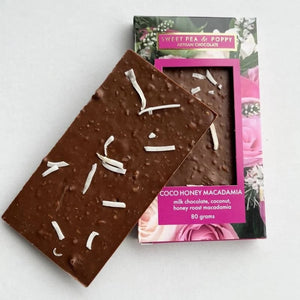 Chocolate bar with coconut pieces next to its packaging on a white background