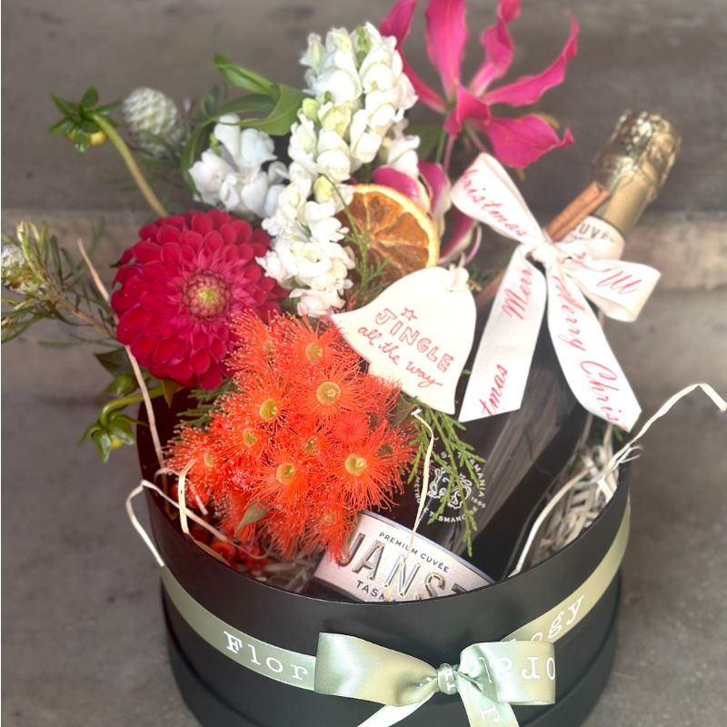 Flowers in a vase, a Christmas ornament and a bottle of Janz Sparkling Wine, presented in a Floral Anthology hamper box.