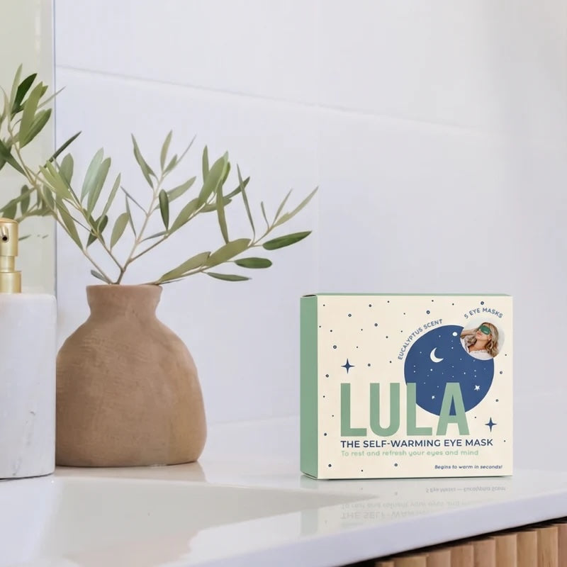 Eucalyptus self-warming eye mask on a shelf with a vase and plant in the background