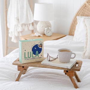 Eucalyptus eye mask sitting on a Wooden tray on a bed.