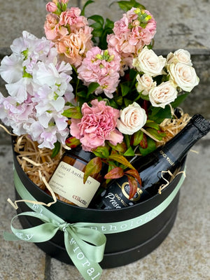 A gift box filled with flowers, candle and Prosecco.