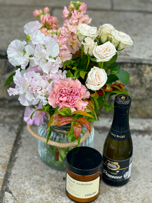 A gift box filled with flowers, candle and sparkling wine. Includes a glass vase inside the box.