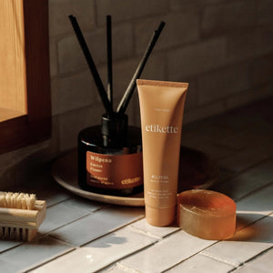tube of Wilpena hand cream on bench top next to a reed diffuser , cake of soap and nail brush.