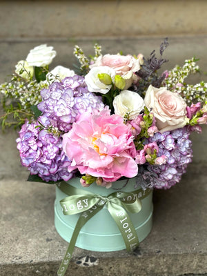 Seasonal flowers in a mini botanical hat box.
