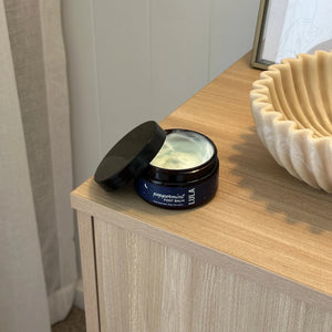 Jar of peppermint wax on a wooden surface with a neutral background