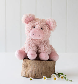Pink plush soft toy  in the shape of a pig on a wooden block with white background