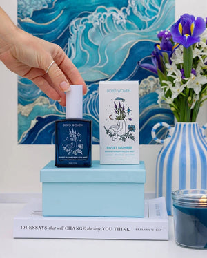 Bottle of Bopo Women Sweet Slumber mist with packaging and a candle on a decorative surface.