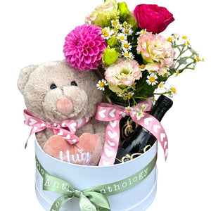 Hamper for Valentine's Day with a plus teddy bear, a bouquet of flowers in a reusable clear glass vase and a bottle of prosecco.