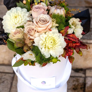 A bouquet of flowers styled in a hat box, no need for a vase.